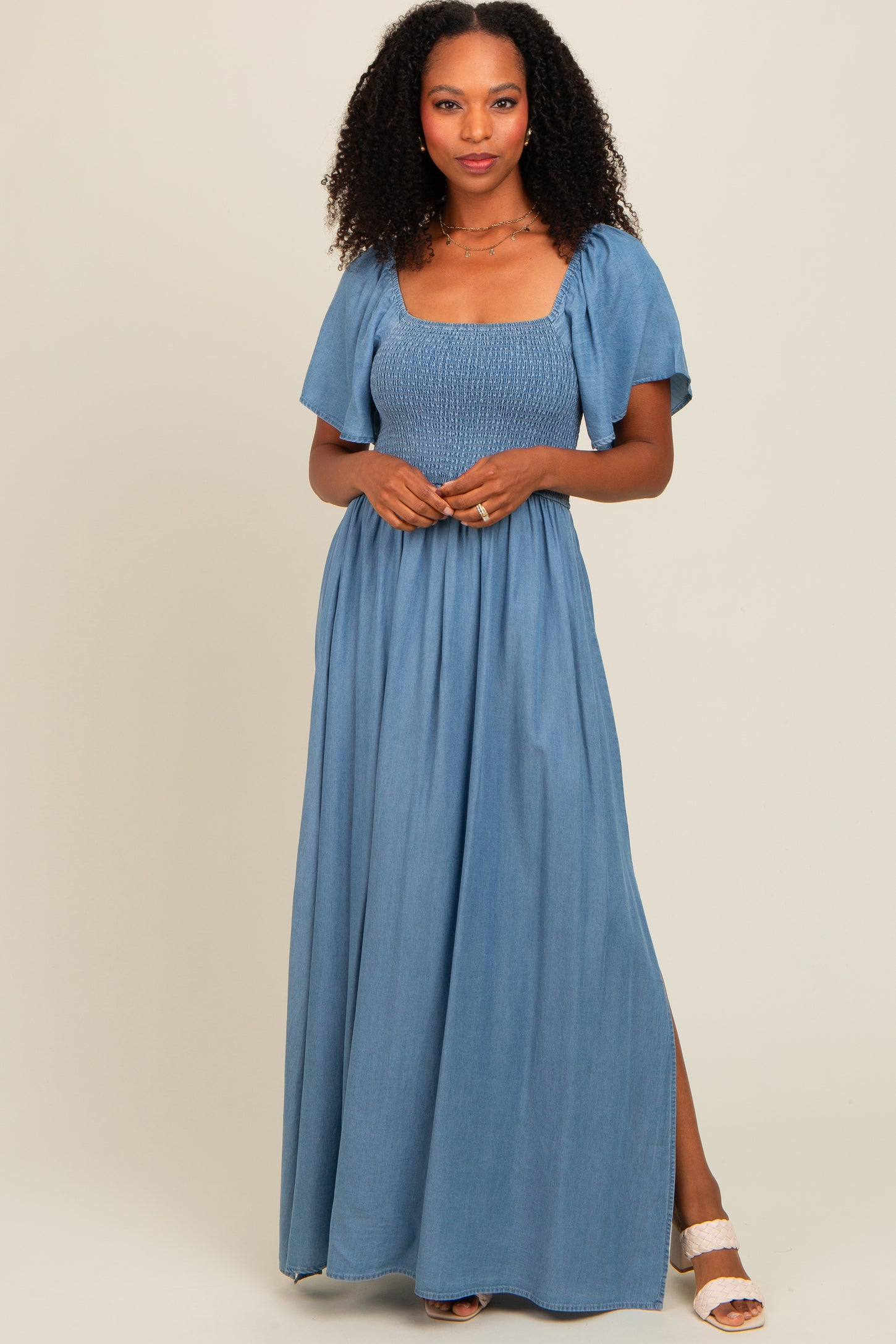 woman wearing a light blue smocked maxi dress with short sleeves and a side slit