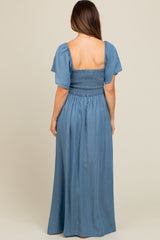 woman wearing a light blue maternity maxi dress with a smocked bodice and short puff sleeves