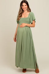 woman wearing a sage green maternity maxi dress with a smocked bodice and flutter sleeves, showing a baby bump