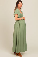 woman wearing a sage green maternity maxi dress with smocked bodice and flutter sleeves, showcasing a baby bump