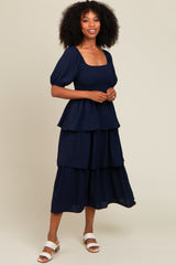 woman wearing a navy blue tiered midi dress with short puff sleeves and square neckline