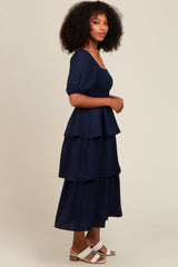 woman wearing a navy blue tiered maxi dress with puff sleeves and a smocked bodice