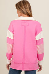 woman wearing a pink maternity sweatshirt with white and striped color block details, showing the back view
