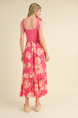 woman wearing a pink floral maxi dress with ruffle details and adjustable straps, view from the back