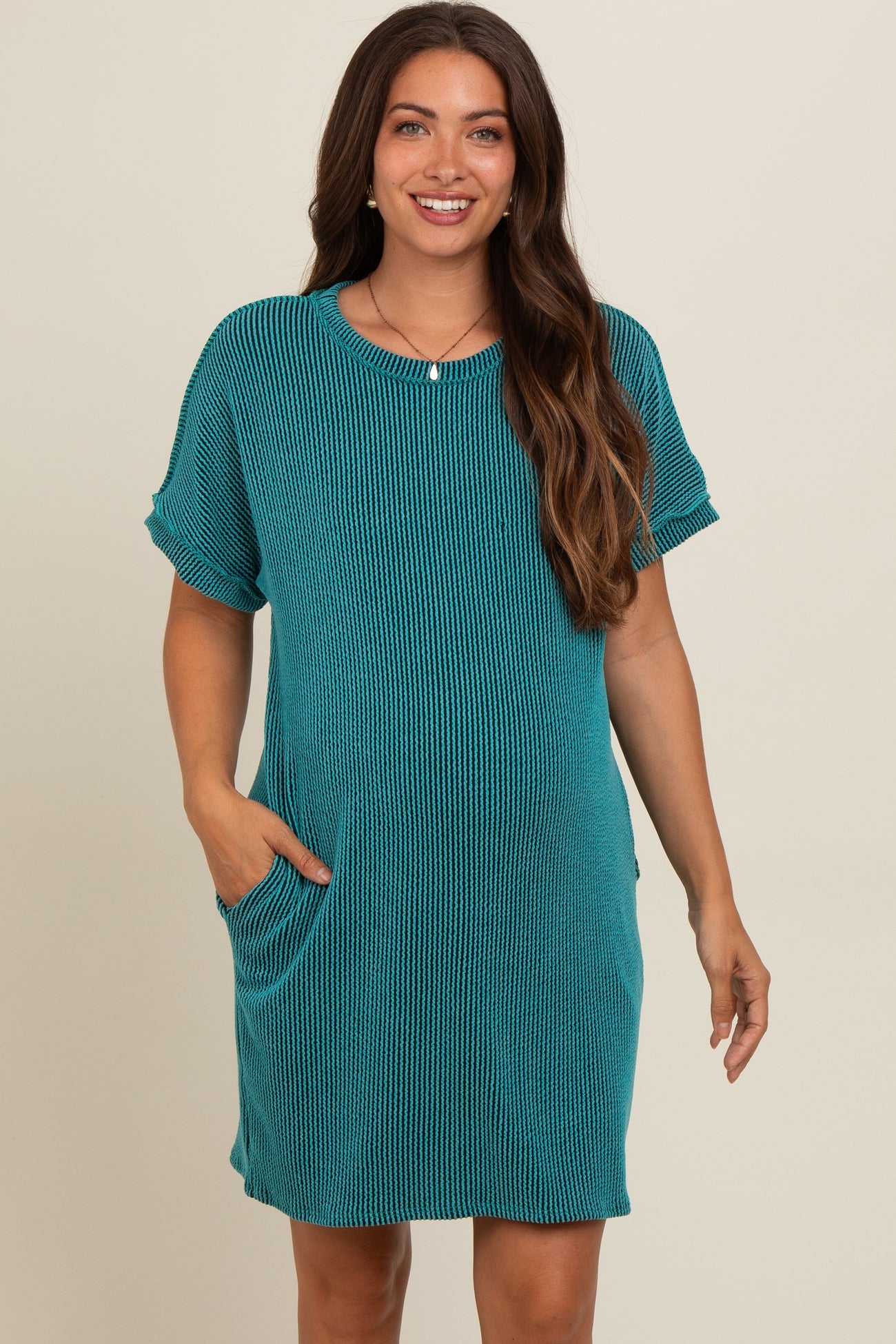 woman wearing a teal striped maternity dress with short sleeves and pockets, showcasing her baby bump