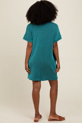woman wearing a teal striped oversized t-shirt dress with short sleeves, seen from the back