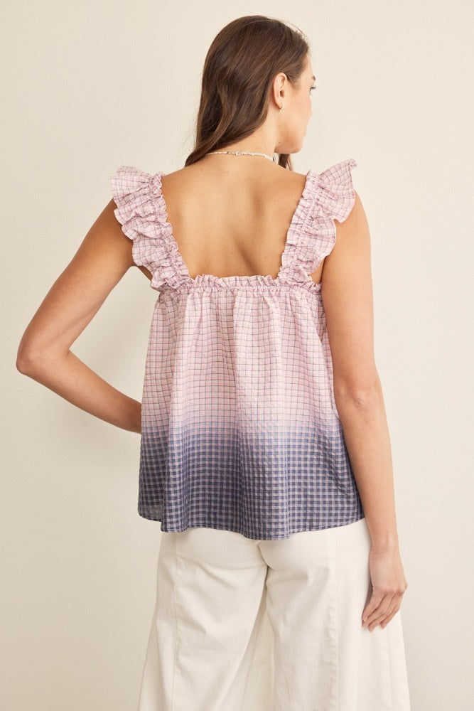woman wearing a pink and blue gradient tank top with ruffle sleeves and a smocked back, styled with white wide-leg pants