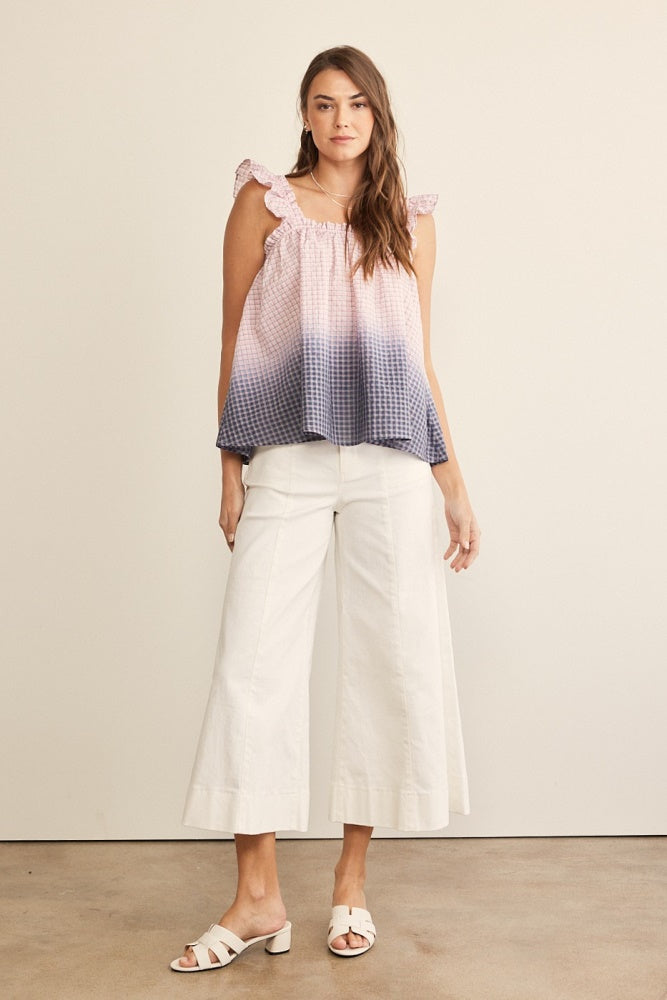 woman wearing a pink and navy blue ombre tank top with ruffle straps and white wide-leg culottes