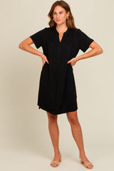 woman wearing a black short sleeve dress with a collared neckline and front placket