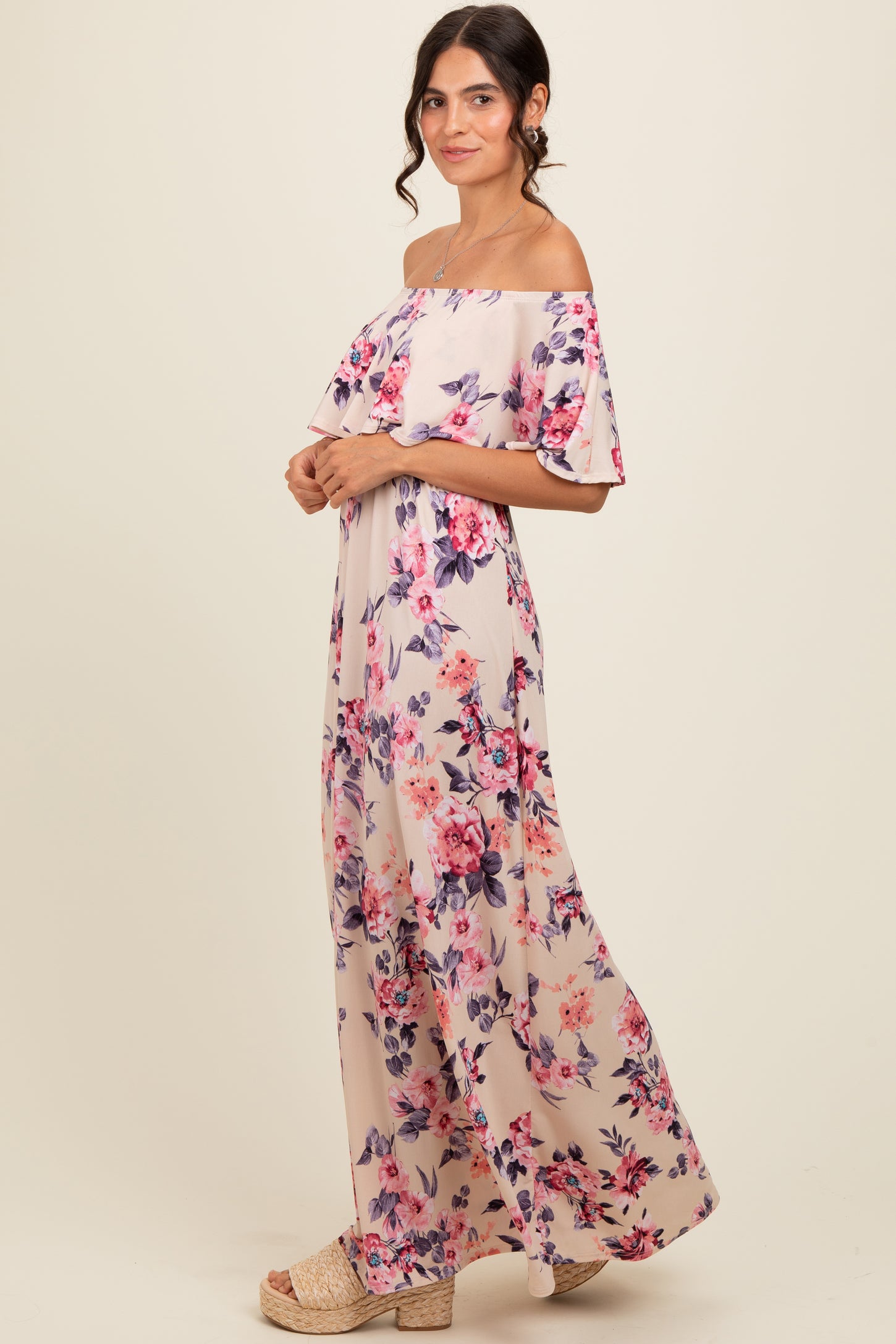 woman wearing a floral off-shoulder maxi dress in soft pink hues with ruffled sleeves and a relaxed fit