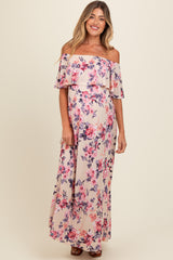 woman wearing a floral off-shoulder maxi maternity dress with a flowy design and a visible baby bump