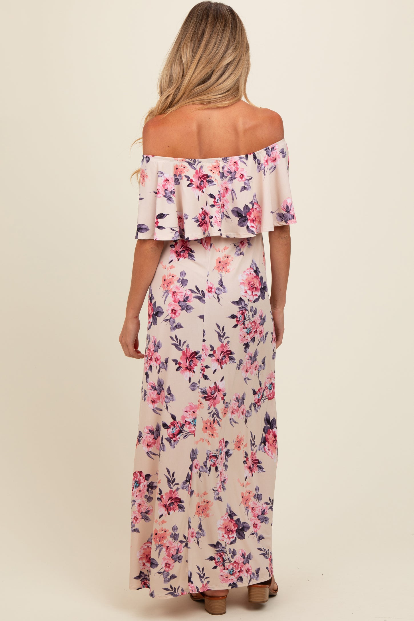 woman wearing a floral off-the-shoulder maxi maternity dress, showing a hint of a baby bump from the back