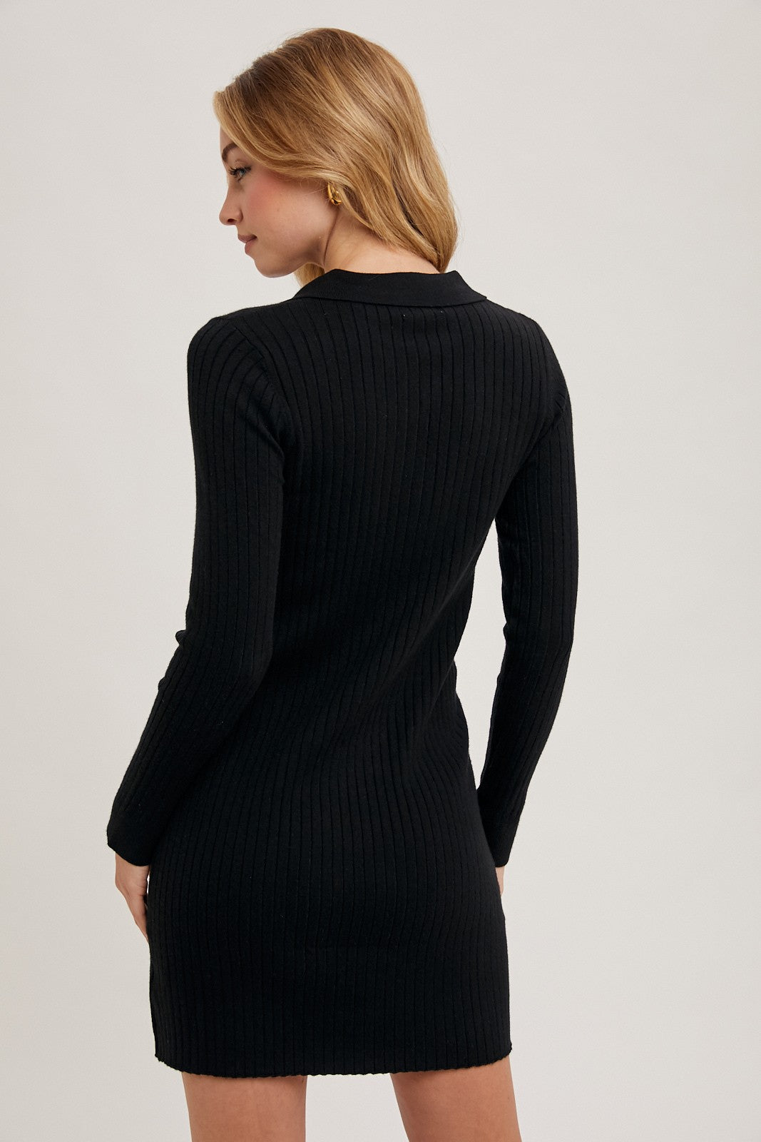 woman wearing a black ribbed long sleeve dress viewed from the back