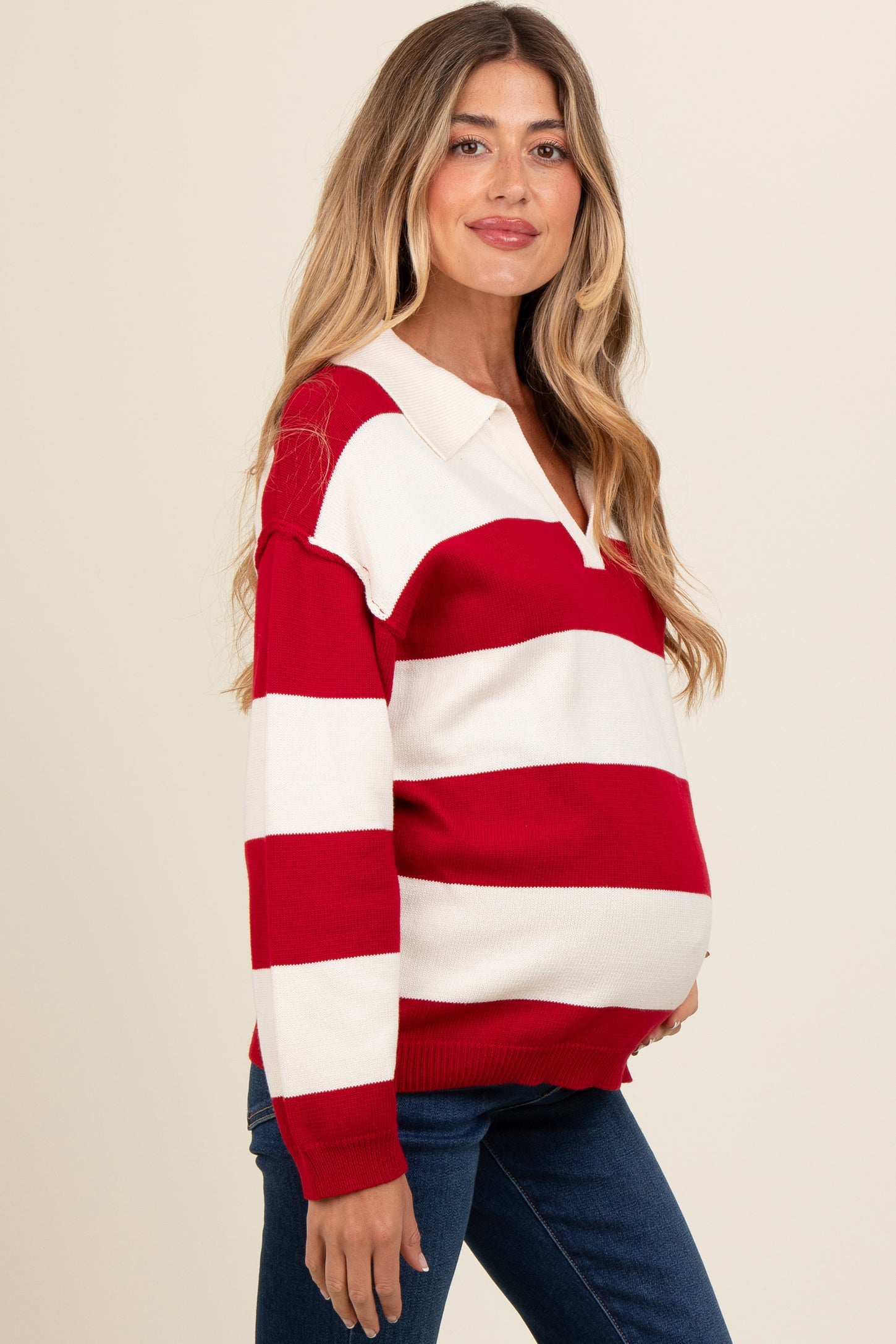 woman wearing a red and white striped maternity sweater with a polo collar and showing her baby bump