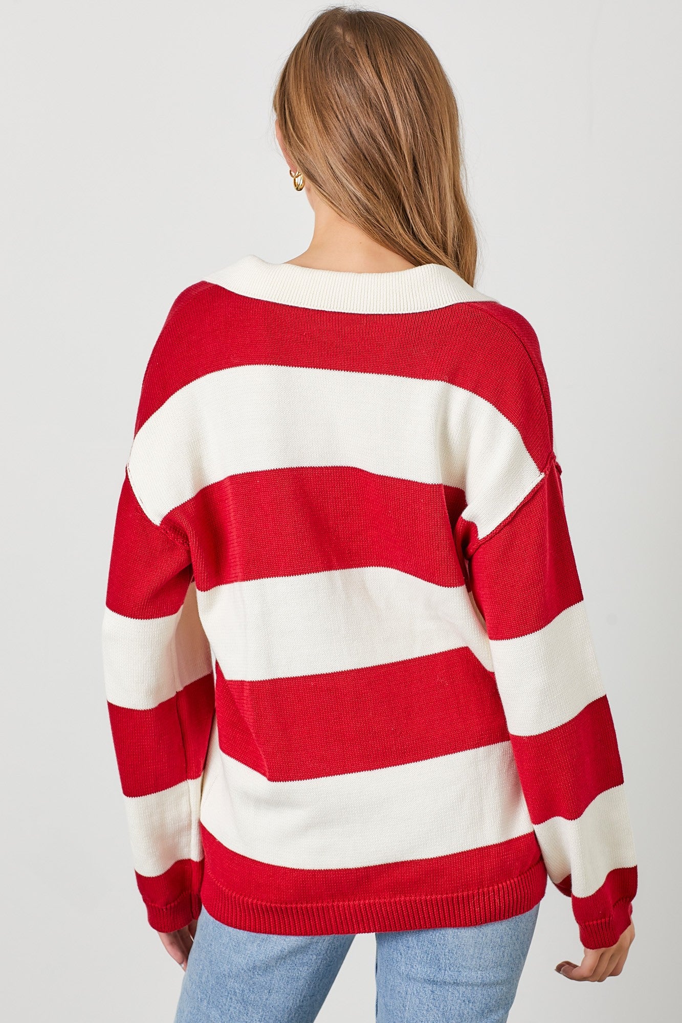 woman wearing a red and white striped oversized sweater, showing the back with a relaxed fit and dropped shoulders