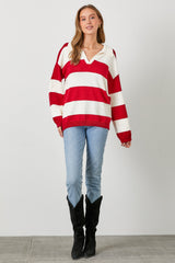 woman wearing a red and white striped oversized sweater with a v-neck and light blue jeans, paired with black boots