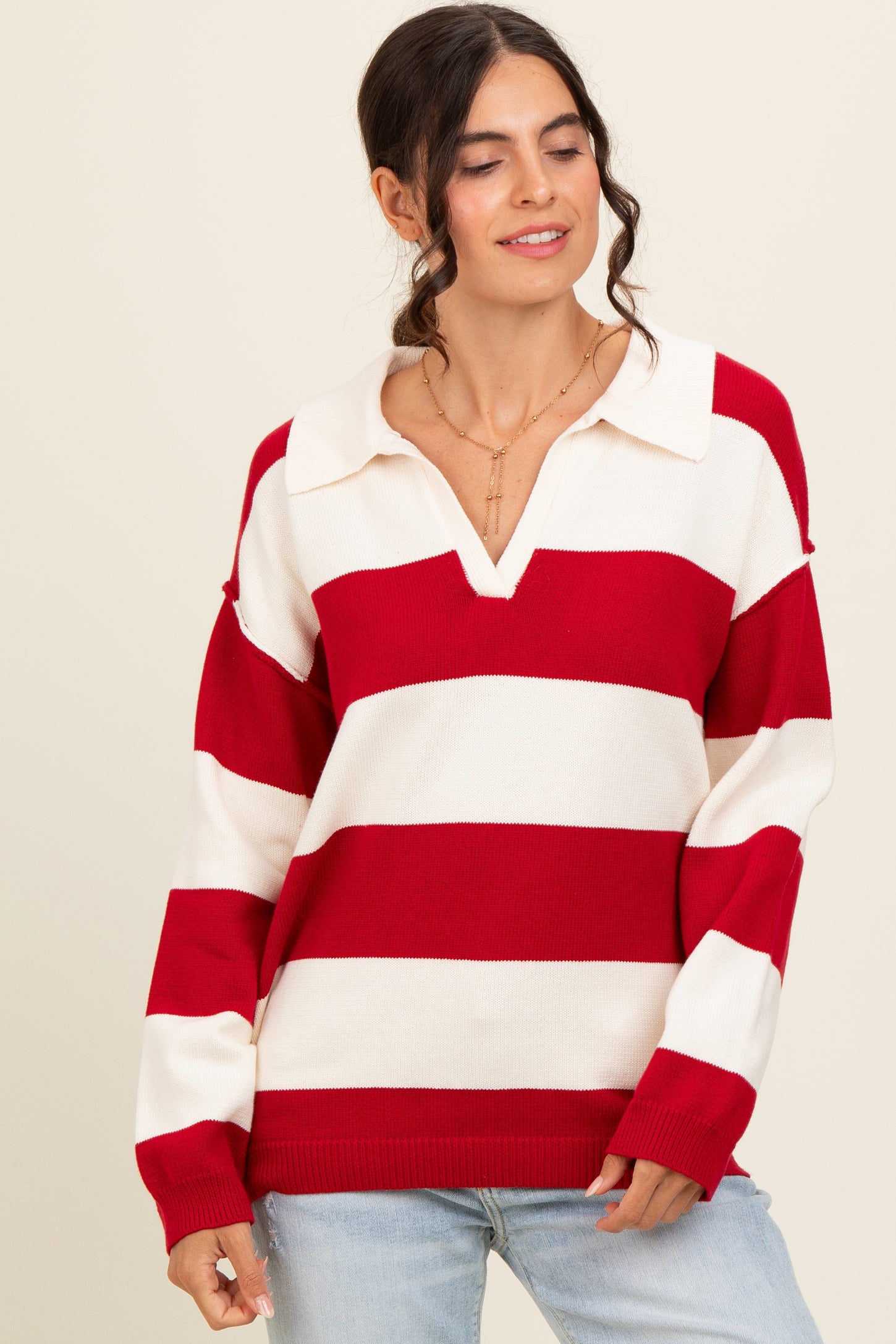 woman wearing a red and white striped oversized sweater with a collar and v-neckline, paired with light blue jeans