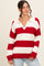 woman wearing a red and white striped oversized sweater with a collar and v-neckline, paired with light blue jeans