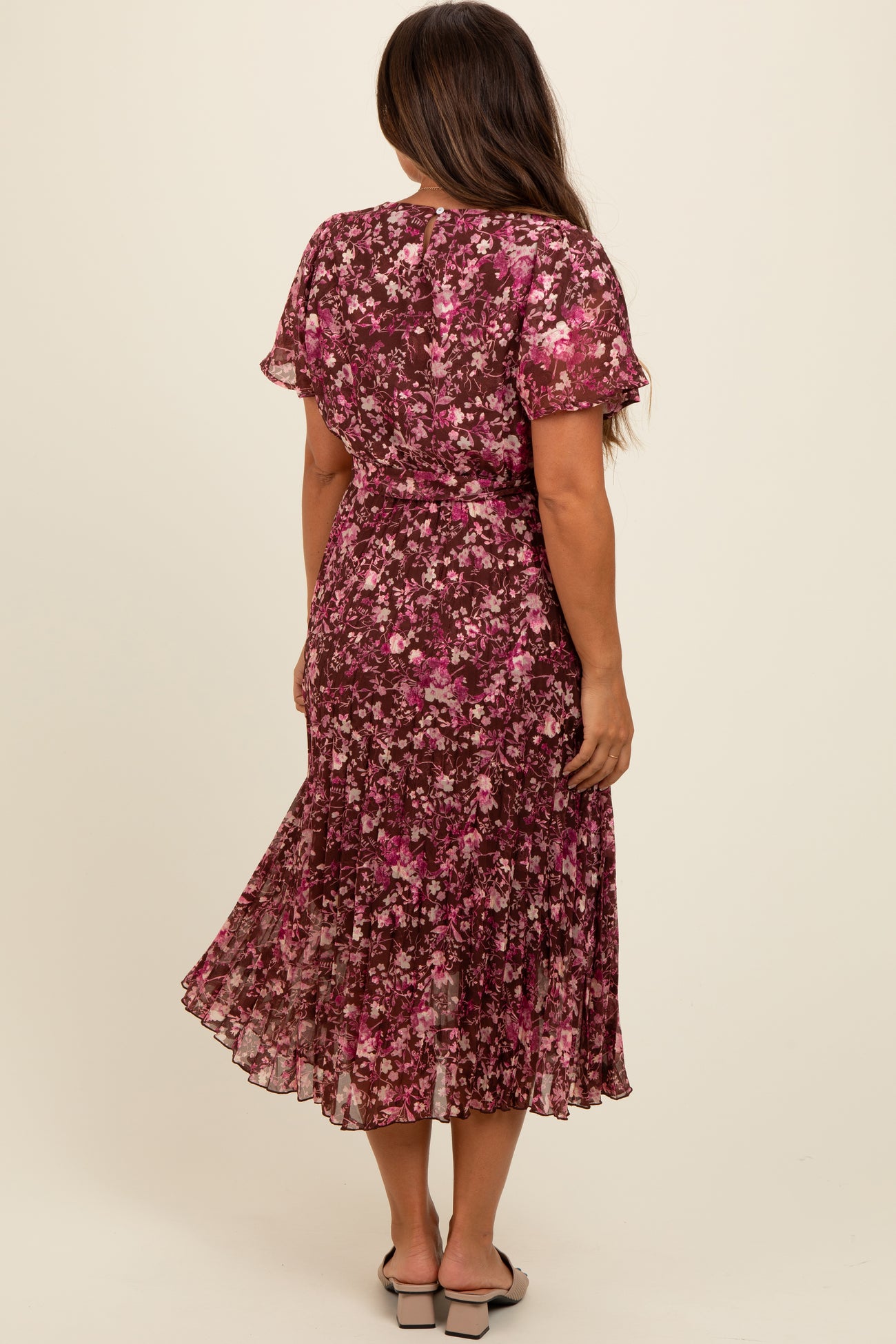 woman wearing a floral midi maternity dress in shades of pink and purple, with short sleeves and a flared skirt