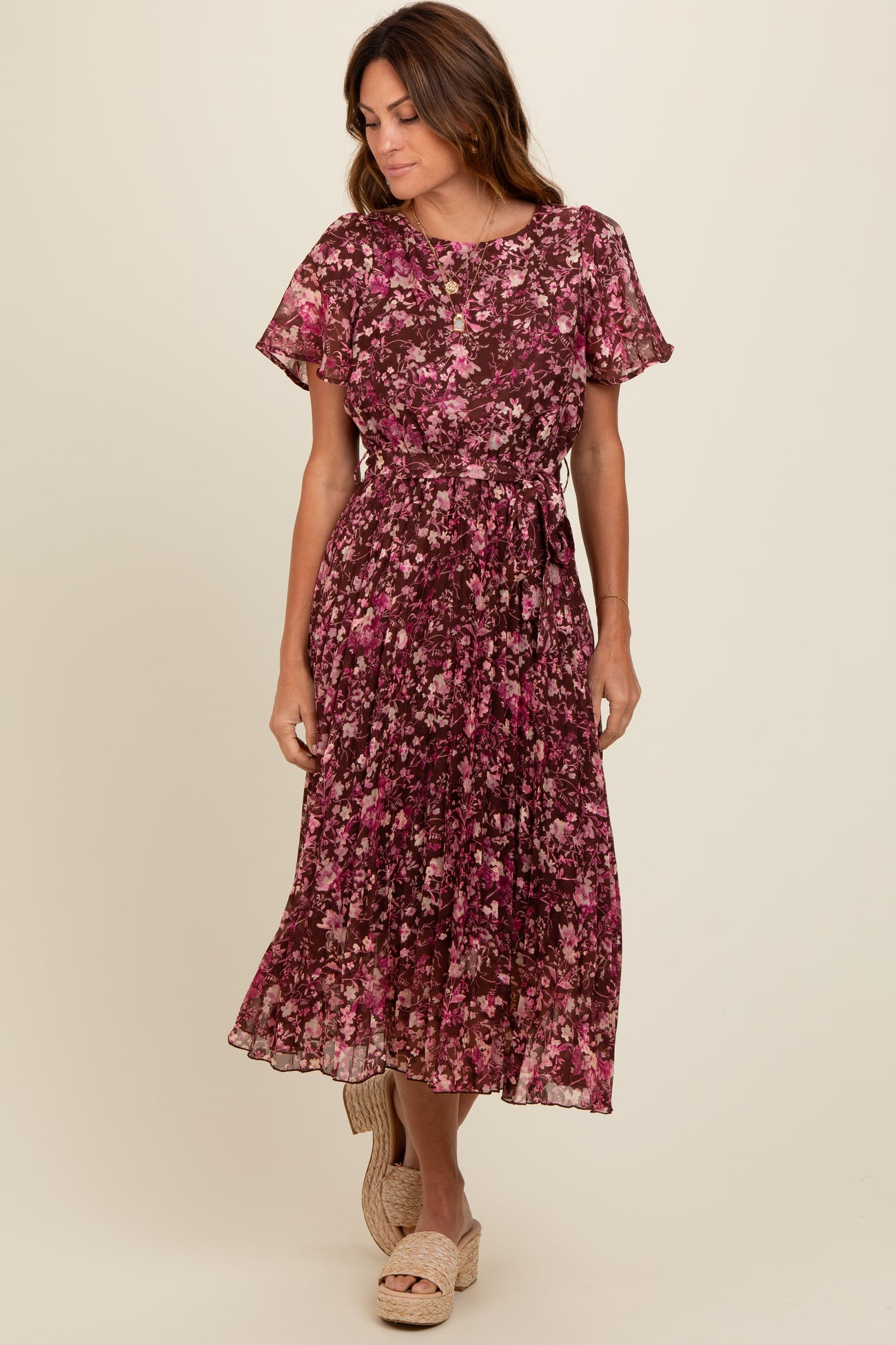 woman wearing a burgundy floral midi dress with short sleeves and a tie waist, standing and smiling
