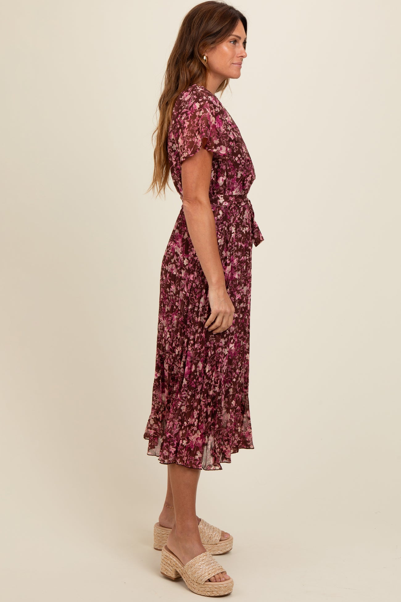 woman wearing a purple floral midi dress with short sleeves and a tie at the waist, styled with platform sandals