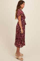 woman wearing a purple floral midi dress with short sleeves and a tie at the waist, styled with platform sandals