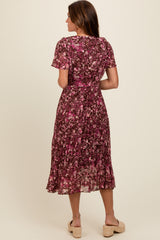 woman wearing a burgundy floral midi dress with short sleeves and a tiered skirt, viewed from the back