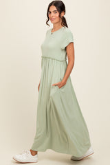 woman wearing a light green maxi dress with short sleeves and side pockets, standing in profile with a casual look