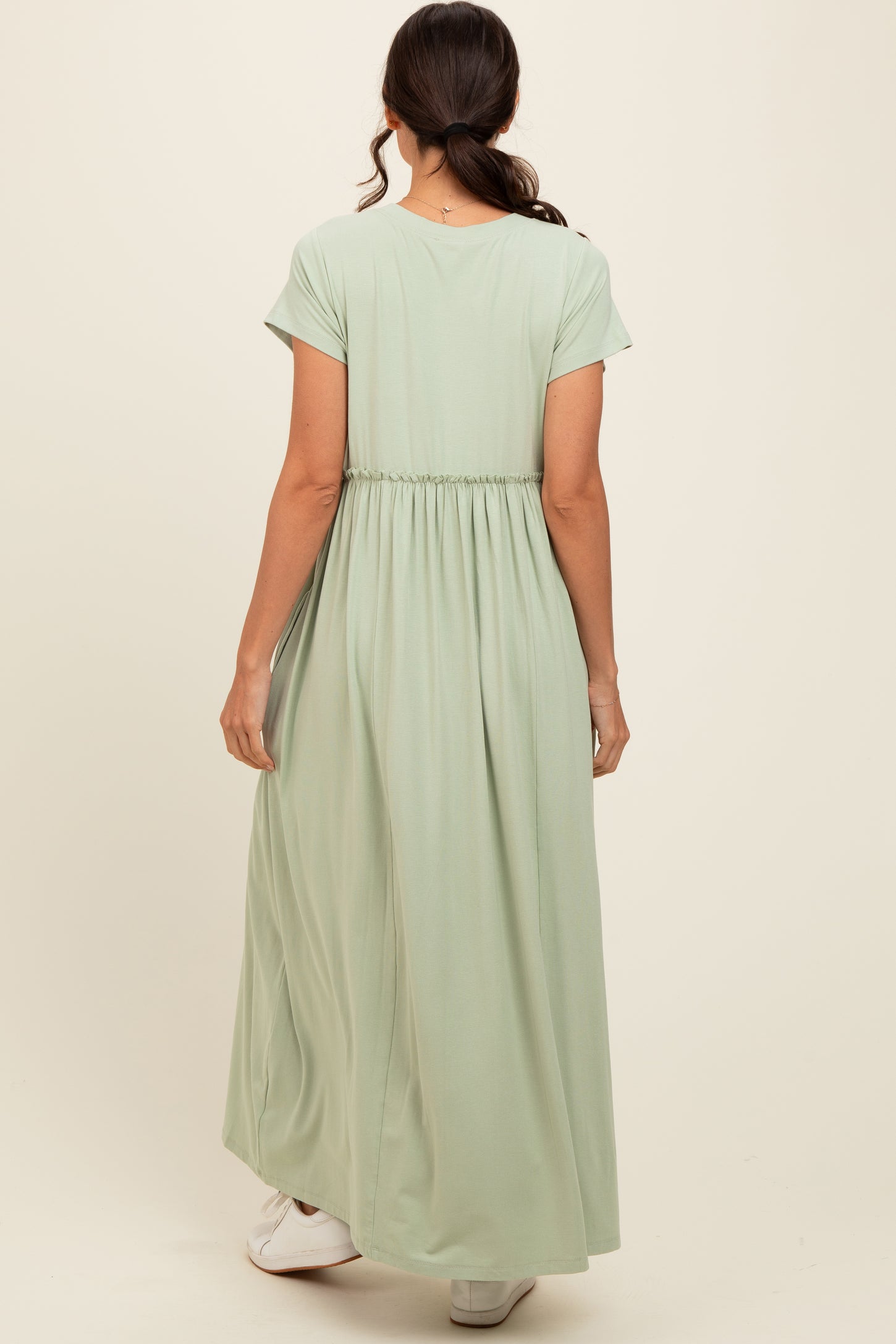 woman wearing a mint green maxi dress with a cinched waist and short sleeves, viewed from the back