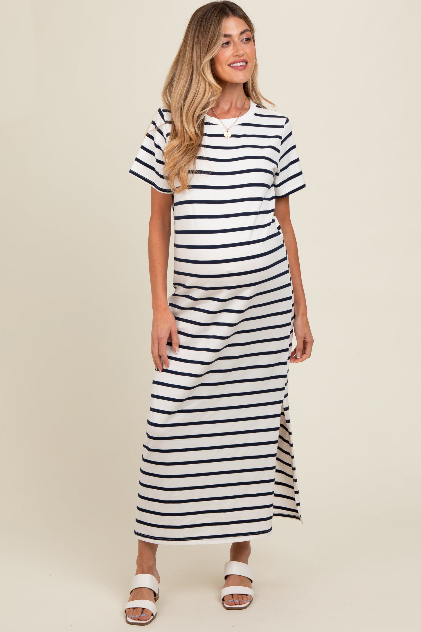 woman wearing a striped maternity maxi dress with a side slit and short sleeves, showing her baby bump