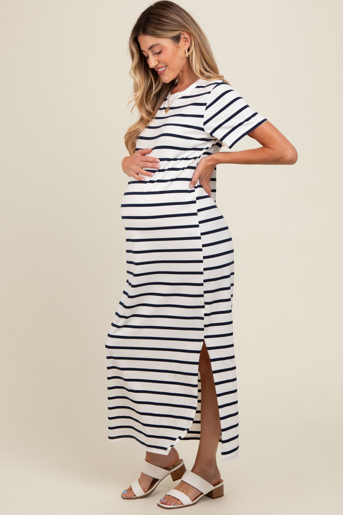 woman wearing a navy and white striped maternity maxi dress, showing her baby bump with side slits and short sleeves