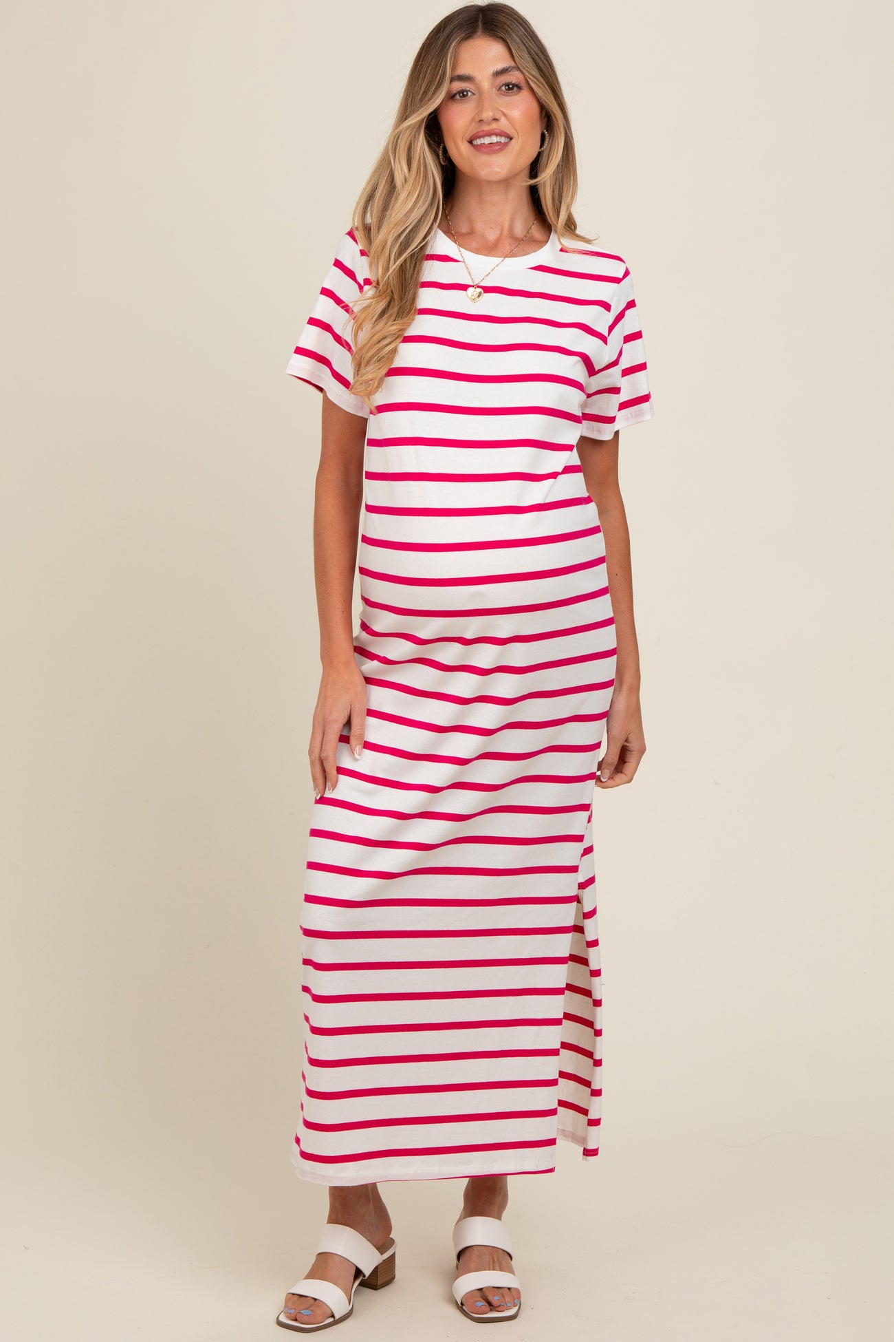 woman wearing a white and pink striped maternity maxi dress with a side slit and short sleeves, showing her baby bump