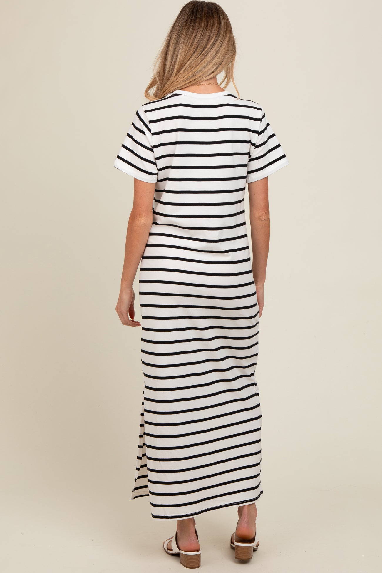 woman wearing a black and white striped maternity maxi dress with short sleeves and a side slit