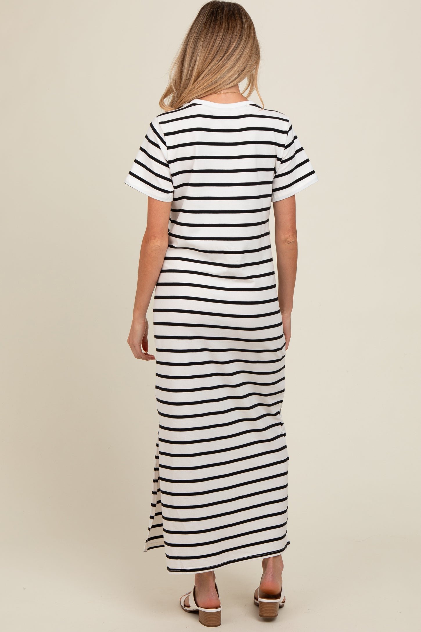 woman wearing a black and white striped maternity maxi dress with short sleeves and a side slit