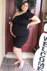 woman wearing a black one-shoulder maternity dress with ruffles and holding her baby bump