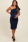 woman wearing a navy one-shoulder maternity dress with ruffle detail and holding her baby bump
