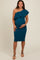 woman wearing a teal one-shoulder maternity dress with ruffle detail and holding her baby bump