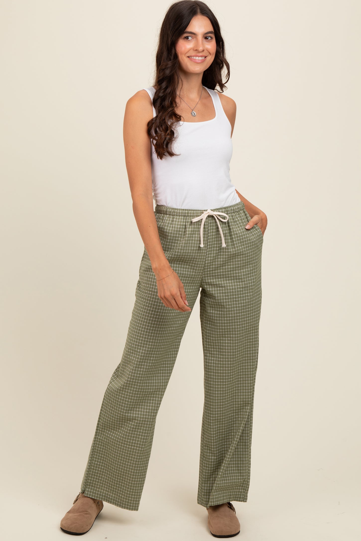 woman wearing a white tank top and green checkered wide-leg pants with a drawstring waist