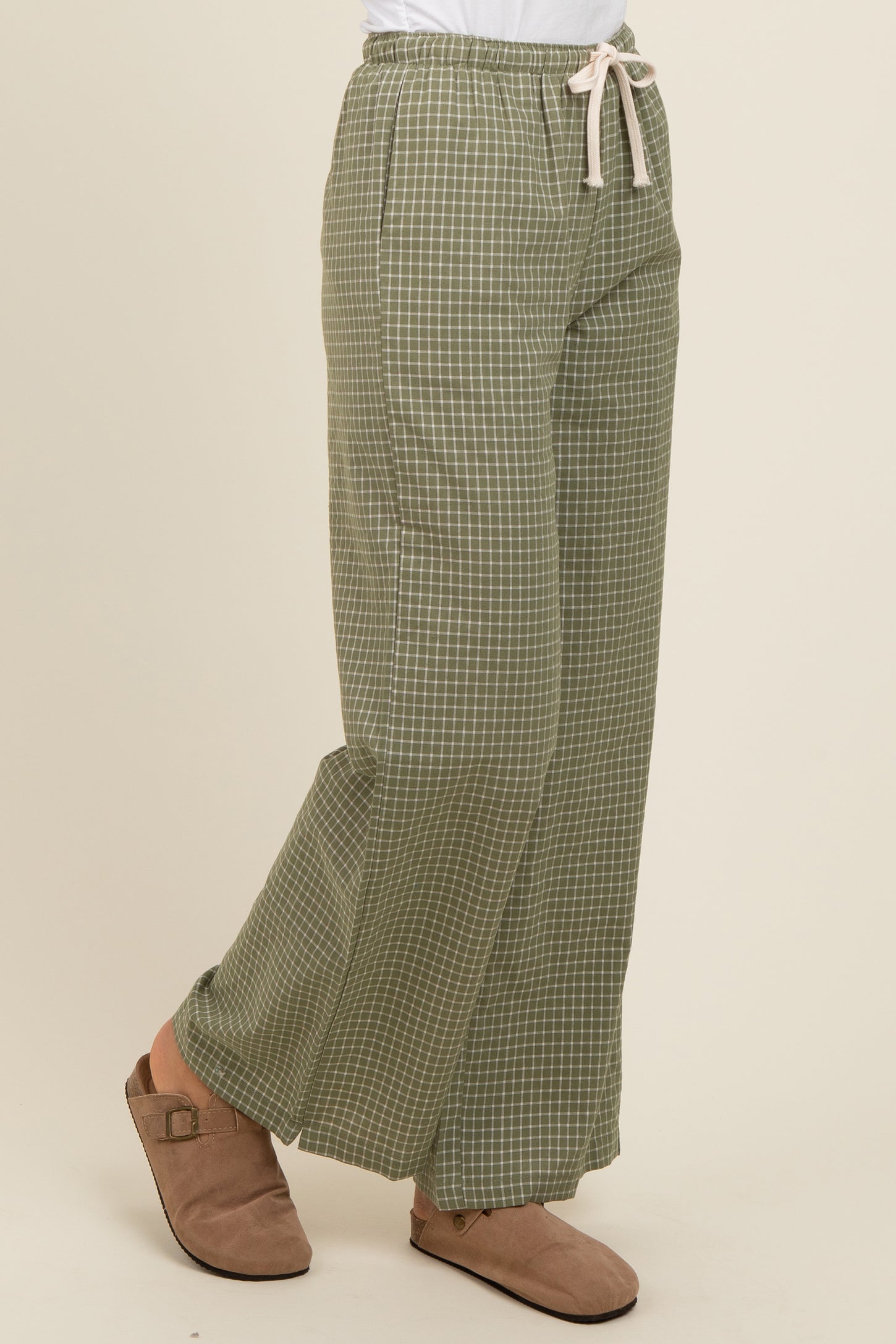 woman wearing green checked wide-leg pants with a drawstring waist and beige slip-on shoes