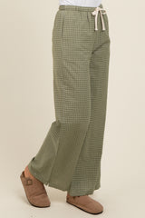 woman wearing green checked wide-leg pants with a drawstring waist and beige slip-on shoes