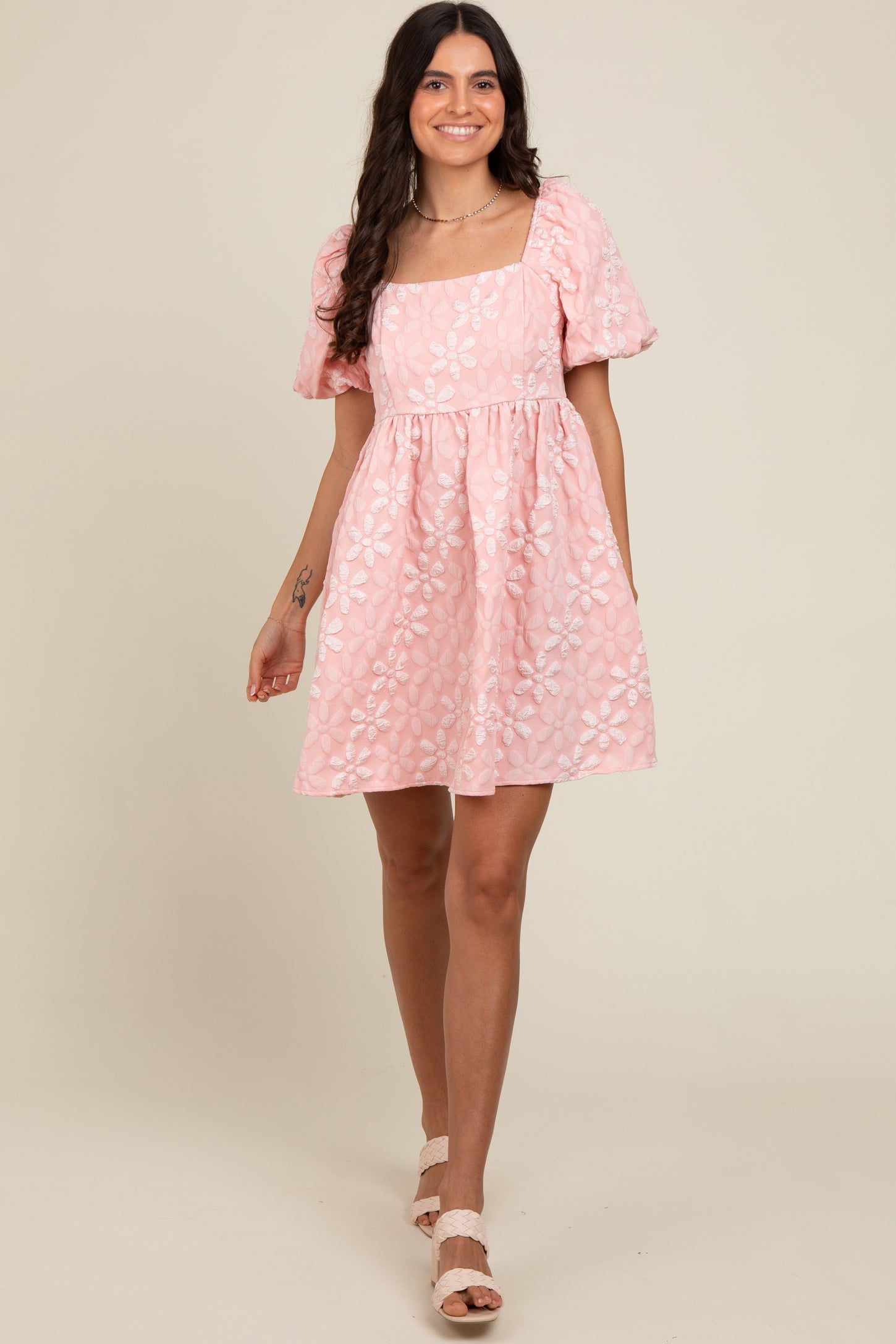 woman wearing a pink puff sleeve square neck dress with floral embroidery and a flared skirt