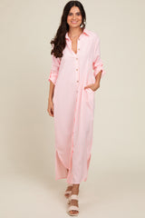 woman wearing a pink and white striped long button-up shirt dress with rolled sleeves and side pockets