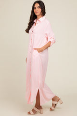 woman wearing a light pink and white striped long button-up dress with side pockets and rolled-up sleeves