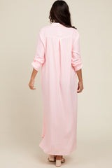 woman wearing a long pink and white striped maxi dress with rolled-up sleeves, seen from the back