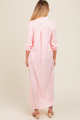 woman wearing a pink and white striped maternity maxi dress, showing the back view with long sleeves rolled up