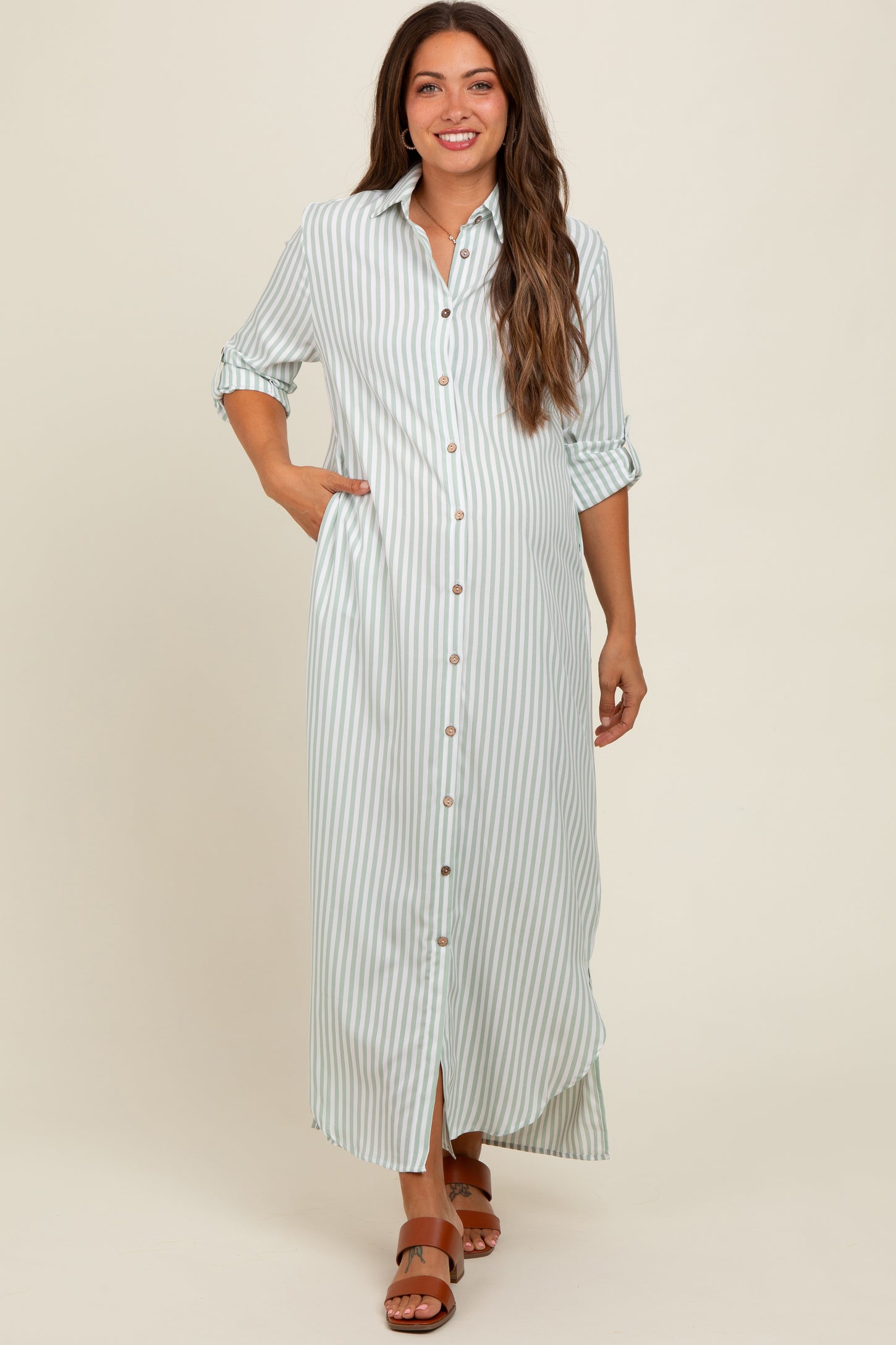 woman wearing a light blue and white striped maternity maxi dress with buttons and rolled sleeves, showing her baby bump