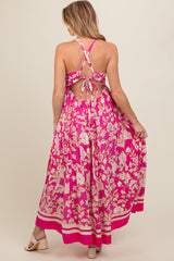 woman wearing a pink floral backless maternity maxi dress with a tie detail and flowing skirt