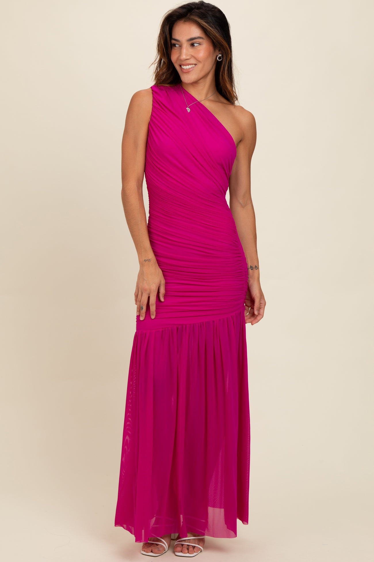 woman wearing a bright pink one-shoulder maxi dress with ruched details and a flowing skirt