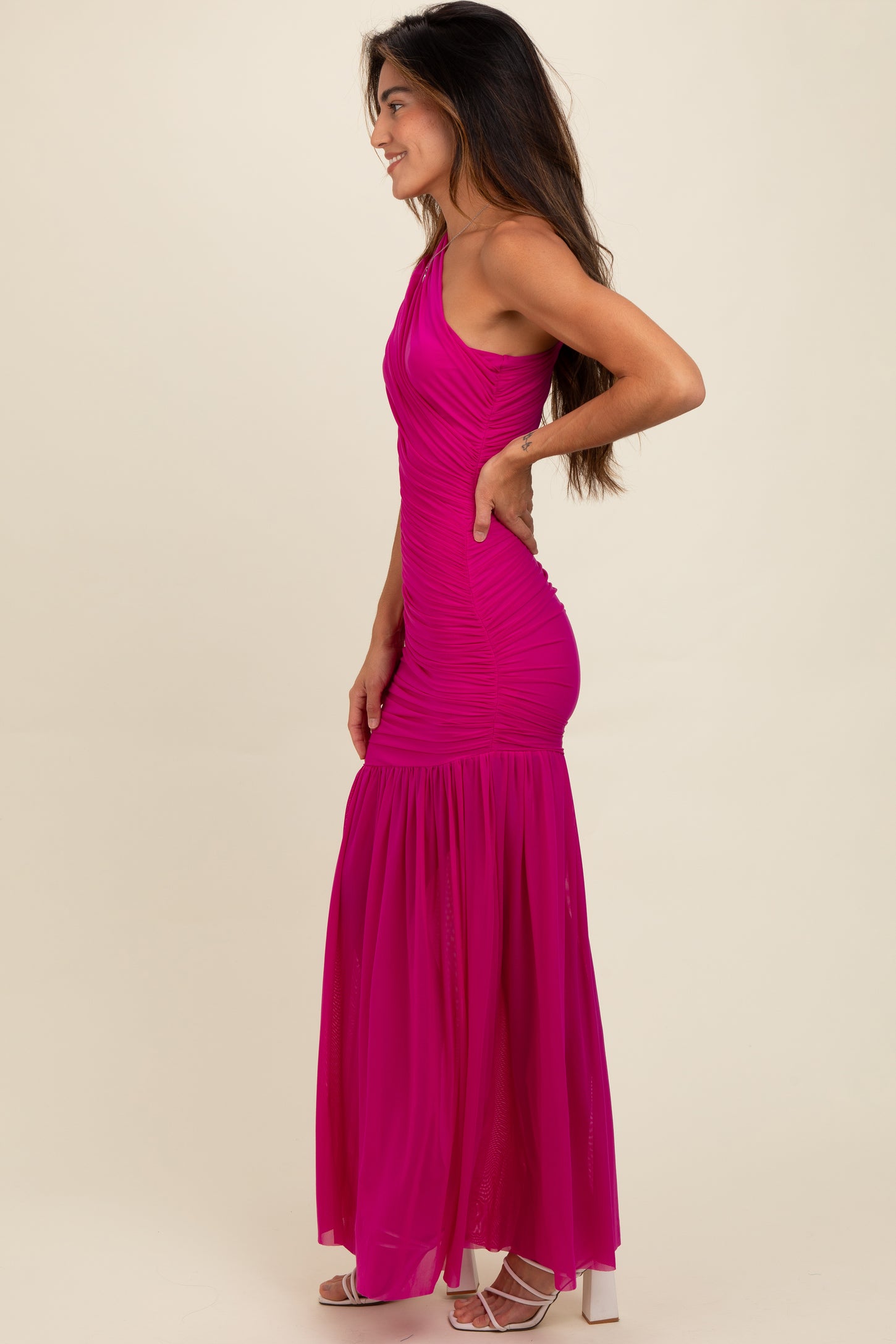 woman wearing a vibrant pink one-shoulder maxi dress with ruched detailing and a flowing skirt
