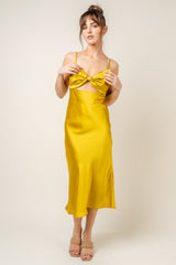woman wearing a yellow satin midi dress with a bow detail and spaghetti straps